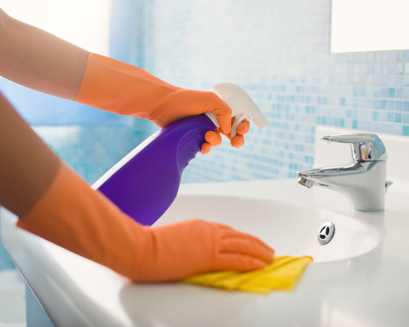 Persona che pulisce il bagno usando un panno e uno spruzzino